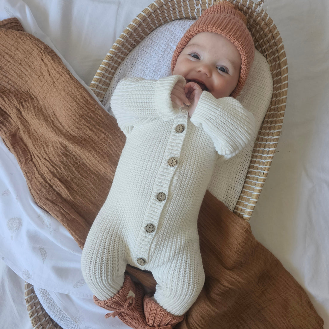 Baby wearing a gender-neutral organic cotton knitted romper, beanie and booties from the Harper Clare newborn bundle