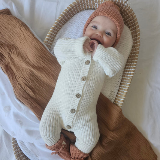 Baby wearing a gender-neutral organic cotton knitted romper, beanie and booties from the Harper Clare newborn bundle