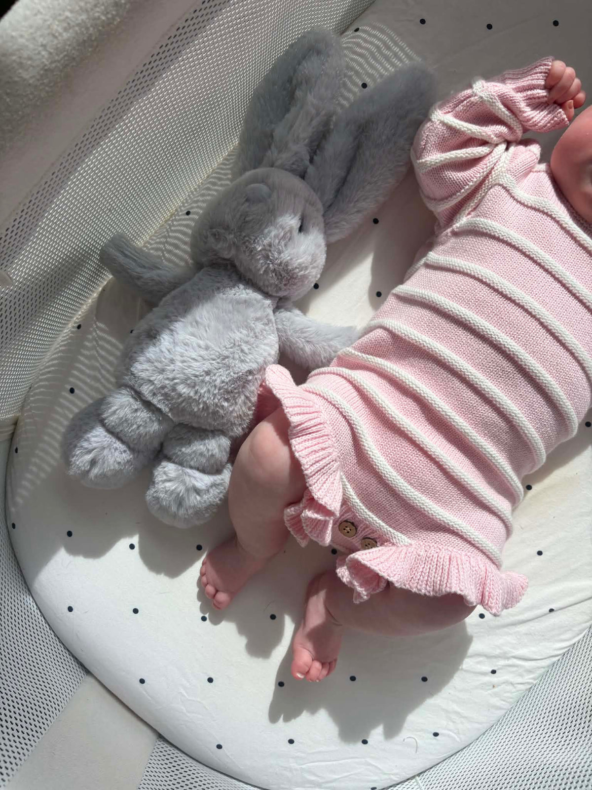 A baby wearing a pink and white striped knit romper