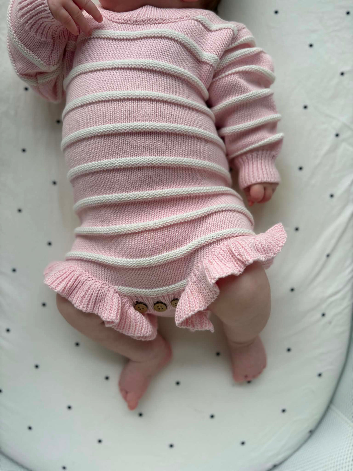 Pink and white ribbed knitted newborn romper made from soft organic cotton, designed for babies 0–3 months