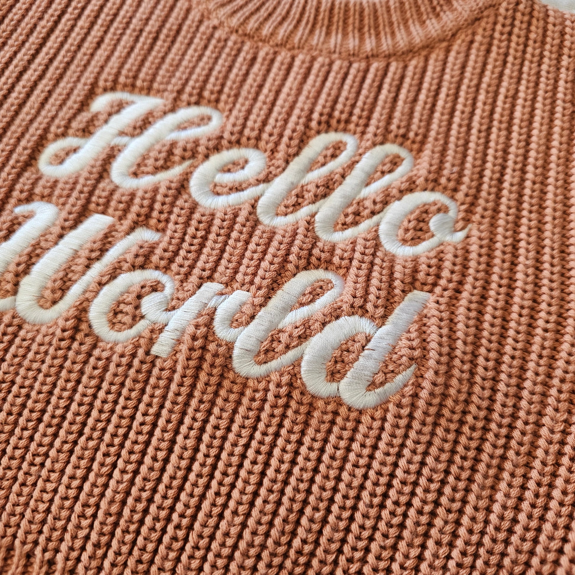 Close-up of embroidered Hello World detail on Dusty Clay baby jumper